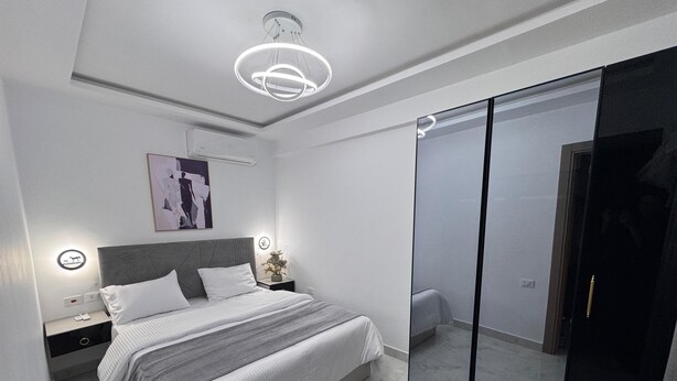 Un dormitorio moderno con cama, mesita de noche y un espejo grande.