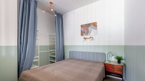 Een slaapkamer met een bed, een nachtkastje, een lamp, een plant, een kunstwerk aan de muur en een kledingkast.