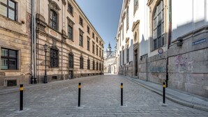 Een straat met kinderafsluitingen en historische gebouwen, bestraat met keien.
