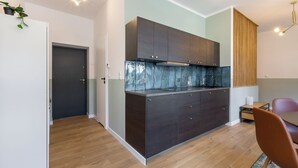 Een moderne keuken met donkere kastjes, een roestvrijstalen afzuigkap en een houten eettafel met een stoel.