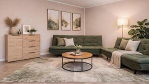 Ein Wohnzimmer mit einem grünen Sofa, einem Couchtisch, einem Schrank und Wandbildern.