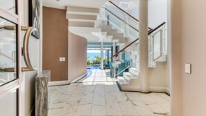 A modern interior with a marble floor, a staircase, and a view to the outside. - Camps Bay 6bed w Ocean Views and Pool Villa Sevara (Cape Town)