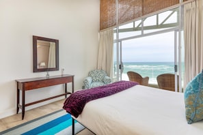 A bedroom with a bed, a nightstand, a mirror, a window with a view of the ocean, and a chair. - Camps Bay 6bed w Ocean Views and Pool Villa Sevara (Cape Town)