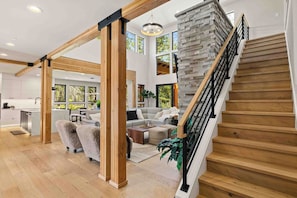 A spacious living area with a staircase, wooden beams, and a stone accent wall. - Memories Are Made Here | Chef's Kitchen & Prime Location (Cle Elum)