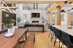 A modern living room with a fireplace, wooden beams, a dining area, and a staircase. - Memories Are Made Here | Chef's Kitchen & Prime Location (Cle Elum)