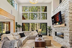 A modern living room with a large sectional sofa, a fireplace, and a TV mounted on a stone wall. - Memories Are Made Here | Chef's Kitchen & Prime Location (Cle Elum)