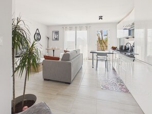 Een moderne woonkamer met een bank, een eettafel en een keukenhoek met een gootsteen en kookplaat.