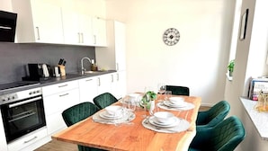 A dining area with a wooden table set for four, surrounded by green upholstered chairs. - VetterLux Bellevue, suite, citycenter Ravensburg (Ravensburg)