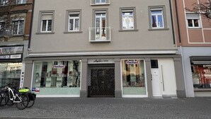 A multi-story building with a ground-floor shop named 'Lola's Outlet' and a visible storefront with a sign that reads 'Neuwertung.' - VetterLux Bellevue, suite, citycenter Ravensburg (Ravensburg)