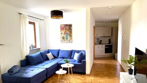 Un salon moderne avec un canapé d’angle, une petite table ronde et une plante en pot.