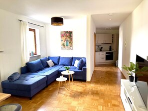 A modern living room with a sectional sofa, a small round table, and a potted plant. - VetterLux Lumi - Balcony, Parking, Greenery view (Ravensburg)