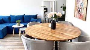 A modern living room with a blue sofa, a round wooden table with two chairs, a small white table, and a potted plant. - VetterLux Nova - bright, quiet & central (Ravensburg)