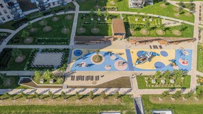 Eine Vogelperspektive eines Parks mit Spielgeräten, Wegen und angelegten Grünflächen.