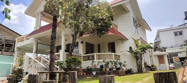 A two-story house with a balcony, potted plants, and a staircase.