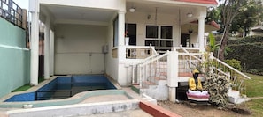 A building with a covered porch, a small pool, and a statue of a deity.