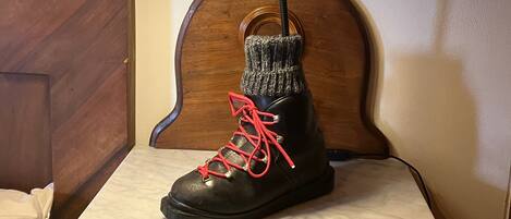 Una bota negra con cordones rojos sobre una mesita de noche con un cajón.