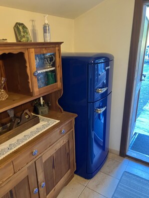 Une cuisine avec des meubles de rangement en bois, un réfrigérateur bleu et une fenêtre donnant sur un beau paysage.