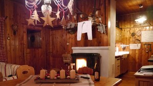 Un intérieur en bois comprenant une table à manger, des bougies, une cheminée et un coin cuisine.