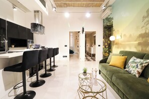 A modern kitchen with black bar stools, a green sofa, and a decorative wall mural. - Luxury Flora Rome. 5 minutes to Colosseum.A perfect place to relax. (Roma)