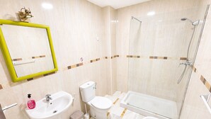 Et badeværelse med vask, toilet og brusebad.