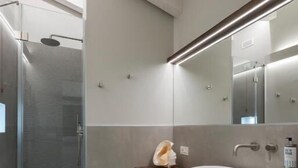 Un baño moderno con cabina de ducha de vidrio, tocador de madera y un espejo grande.
