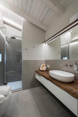 A modern bathroom with a glass shower enclosure, a wooden vanity, and a large mirror. - Cà Amae La Spezia (CADIMARE)