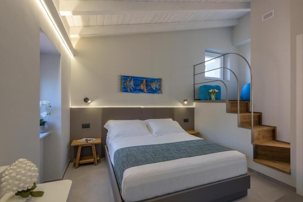 A bedroom with a bed, bedside table, nightstand, and a painting on the wall.
