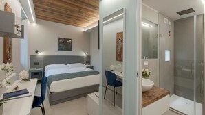 Una habitación de hotel moderna con cama, escritorio, silla y zona de ducha.