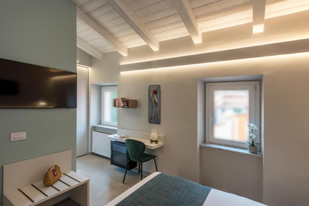 Een moderne slaapkamer met een bed, een bureau, een stoel, een televisie en een raam.