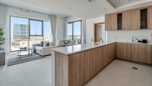 Una cocina moderna con una isla central, ventanas amplias y un comedor con sofá y mesa.