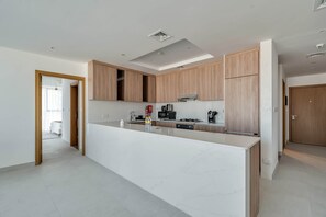 Eine moderne Küche mit Marmorarbeitsplatte, Holzschränken und einer zentralen Kochinsel.