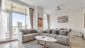 A modern living room with a sofa set, a coffee table, and a large window with curtains. - Free Housekeeping Visits During Your Stay - Stayshort - Elegant 2 Bedroom in Dubai Marina That Sleeps 4 (Dubai)