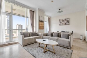 Ein modernes Wohnzimmer mit einer Sofagarnitur, einem Couchtisch und einem großen Fenster mit Vorhängen.