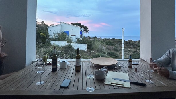 Une table à manger avec des bouteilles de vin, des verres et un téléphone intelligent.