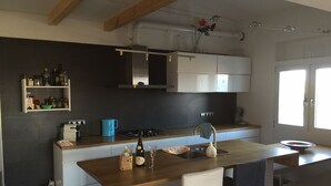 Une cuisine moderne dotée d’un îlot central, de meubles blancs et d’un four encastré.