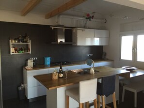 Eine moderne Küche mit einer zentralen Kochinsel, weißen Schränken und einem eingebauten Backofen.