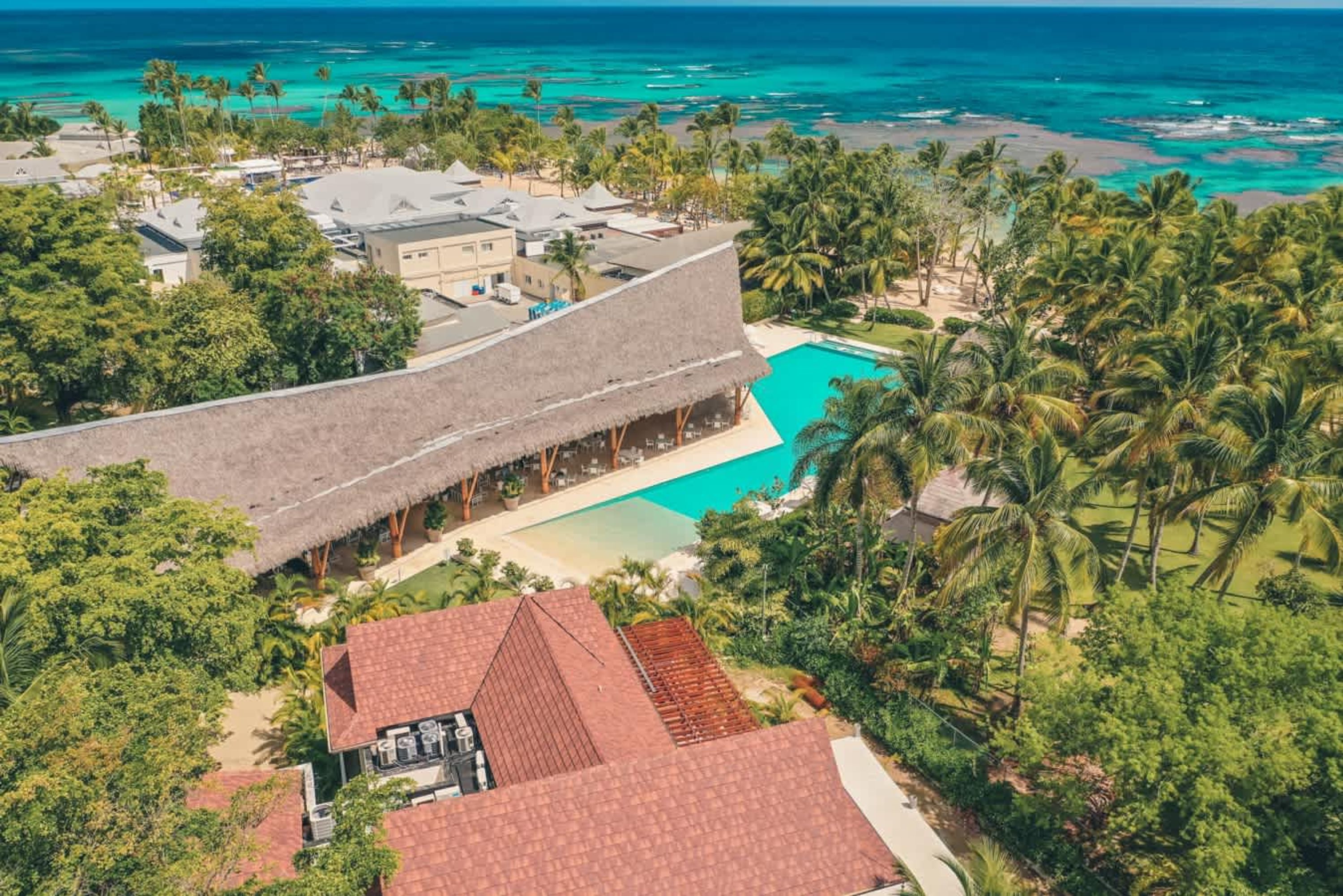 A resort with a large pool, palm trees, and a view of the ocean.