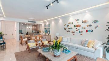 A modern living room with a sofa, coffee table, and dining area.