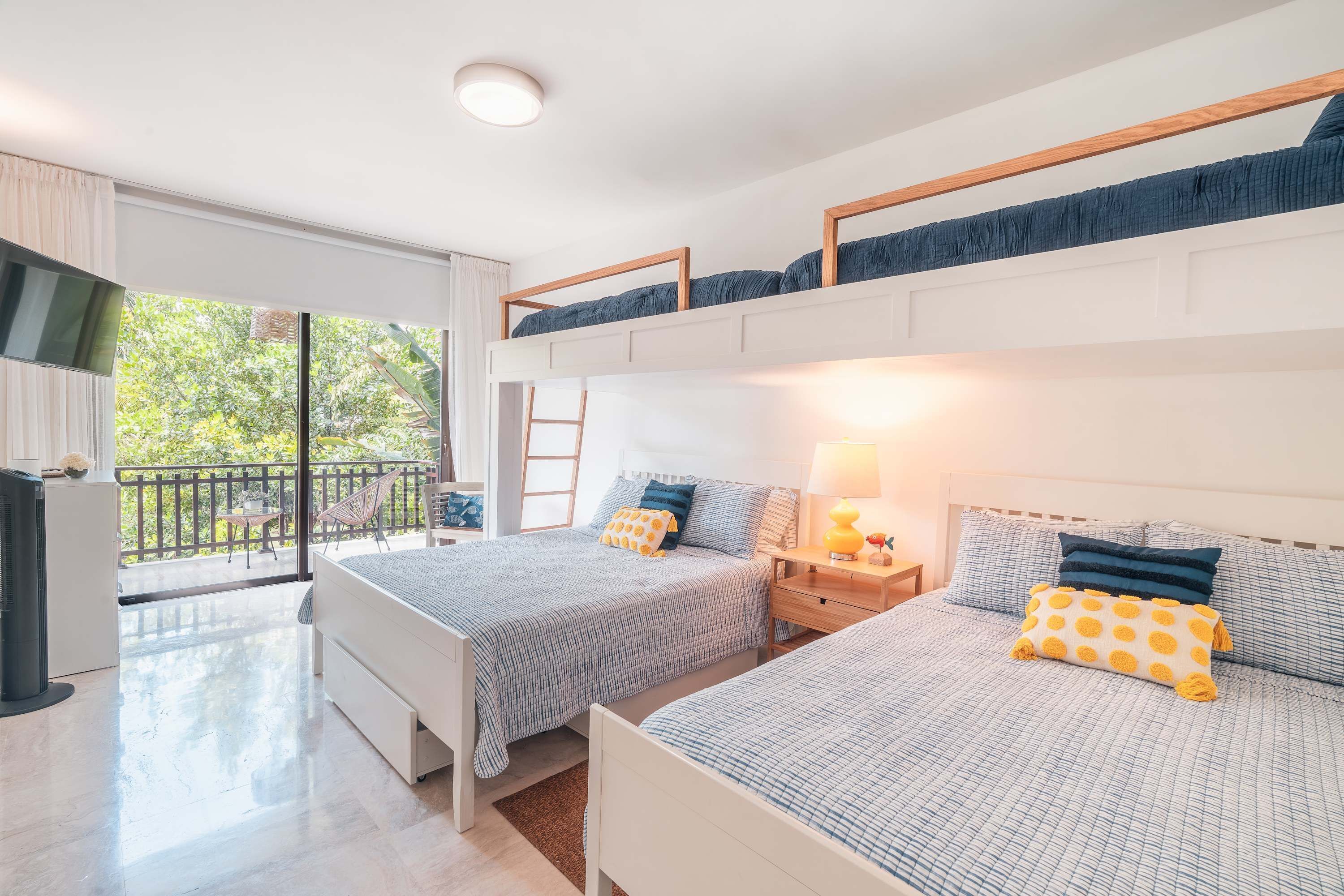 Une chambre avec deux lits, un balcon et une télévision.