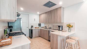 A modern kitchen with a central island, stainless steel appliances, and wooden cabinetry.