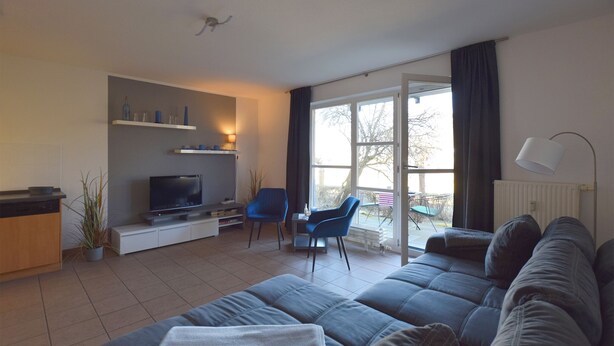 Una sala de estar con sofá, televisión, sillas y un comedor con mesa y sillas.