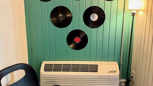 A room with a teal wall, a white air conditioner, and a black chair. - The Vinyl Lounge at The Cedar (Sandusky)