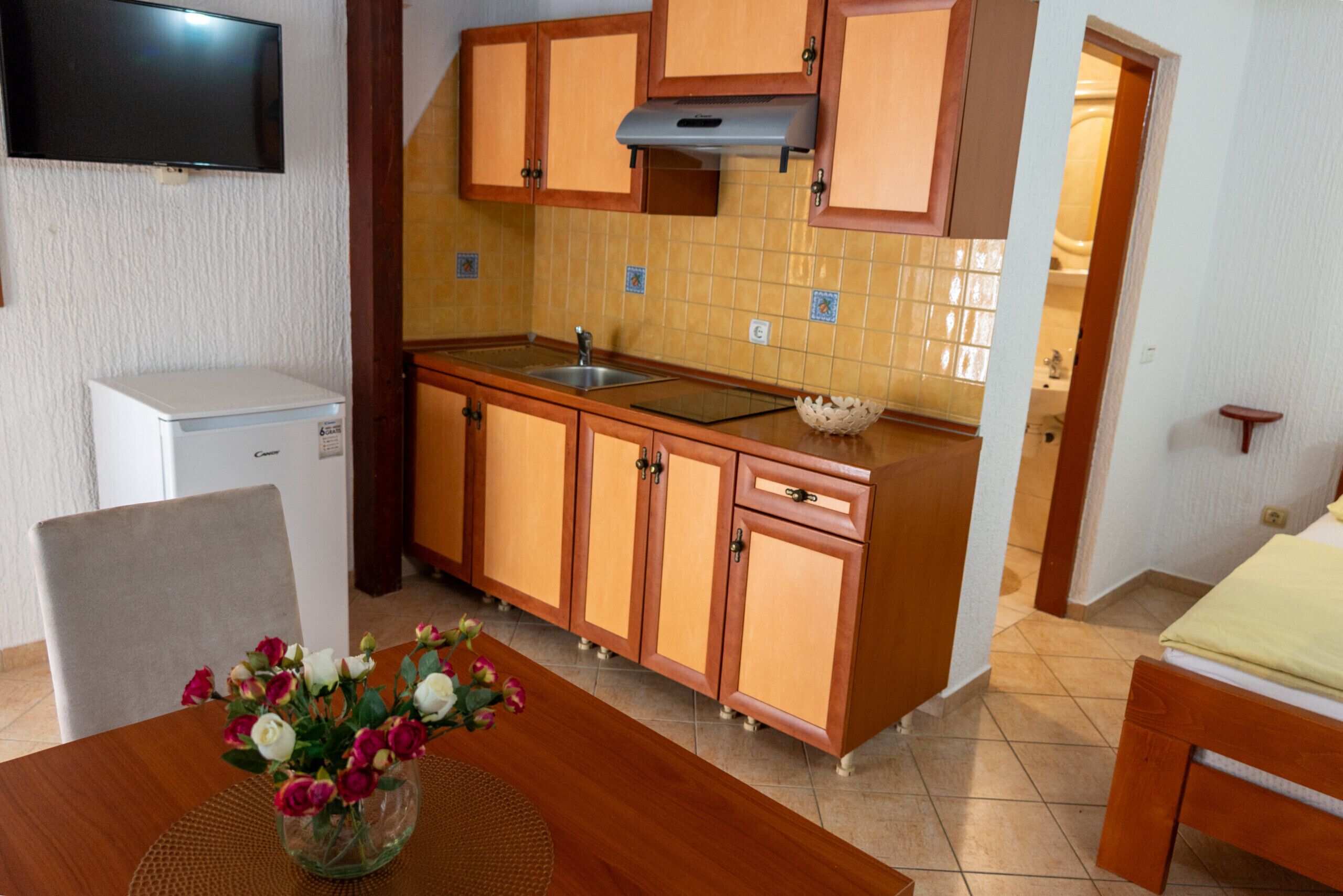 Una cocina compacta con armarios de madera, microondas integrado y salpicadero de azulejos.