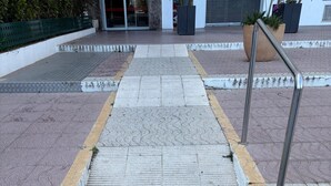Una scala conduce all'ingresso di un edificio, con un percorso tattile a pavimento.
