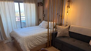 Una camera da letto con un letto, un divano, una scrivania e una finestra con tende.