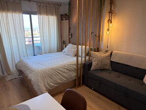 A bedroom with a bed, a sofa, a desk, and a window with curtains. - Tamy-Home@ (Empuriabrava)
