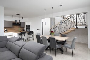 A modern kitchen with a dining area, grey sofas, and a staircase with a metal railing. - Villa Leola in Ližnjan (Ližnjan)