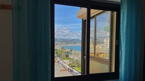 Ein Fenster mit Blick auf eine Küstenlandschaft, darunter ein Strand und Gebäude.