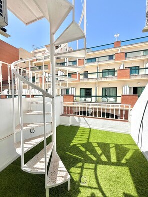 A multi-level outdoor area with a spiral staircase, artificial grass, and a view of a building with multiple balconies. - TERRASOL PENTHOUSE DUPLEX PENTHOUSE CENTER TORRE DEL MAR (Torre del Mar)