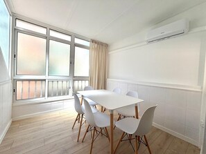 A room with a white table, six chairs, a large window with curtains, and an air conditioning unit on the wall. - TERRASOL PENTHOUSE DUPLEX PENTHOUSE CENTER TORRE DEL MAR (Torre del Mar)